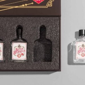 Rigid gift box with a die cut foam insert holding three glass bottles, one cavity empty and one matching bottle removed and set beside the box showing the exact fit