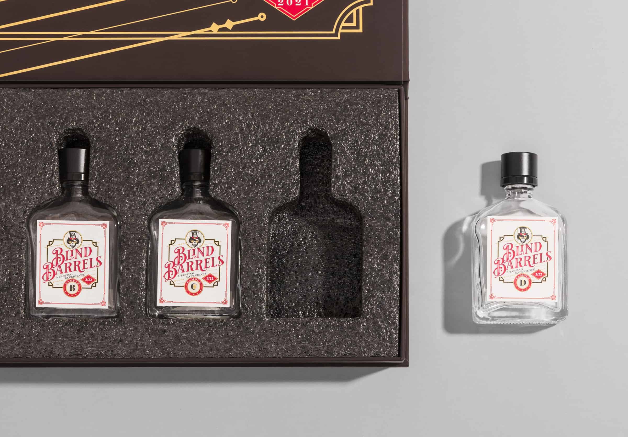 Rigid gift box with a die cut foam insert holding three glass bottles, one cavity empty and one matching bottle removed and set beside the box showing the exact fit