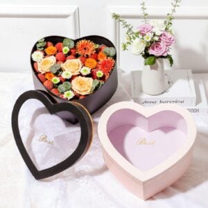 Custom heart shaped boxes with lids in black and pink, one filled with a floral arrangement.