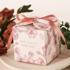 Custom party favor box printed with a floral pattern and finished with a pink ribbon bow on top.