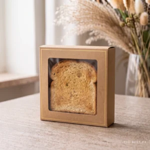 Custom toast box in kraft board with a gold foil border and a clear window die cut into the front panel, showing a thick slice of toast inside.