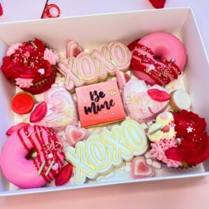 Custom valentine treat box in white, opened to show decorated cookies and sweets arranged inside.