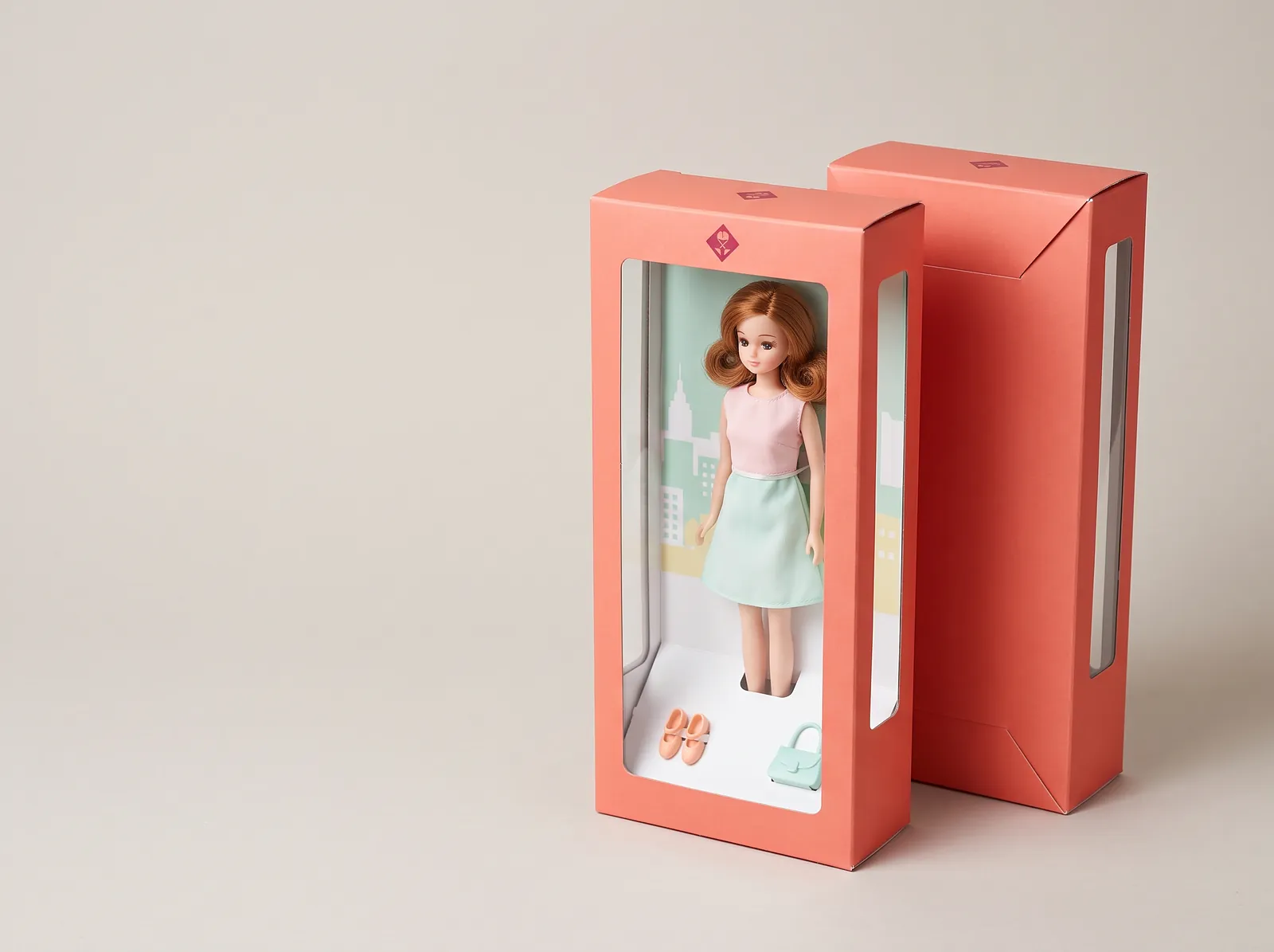 Fashion doll in a tall coral window box with a printed city backer card and slots holding shoes and a handbag