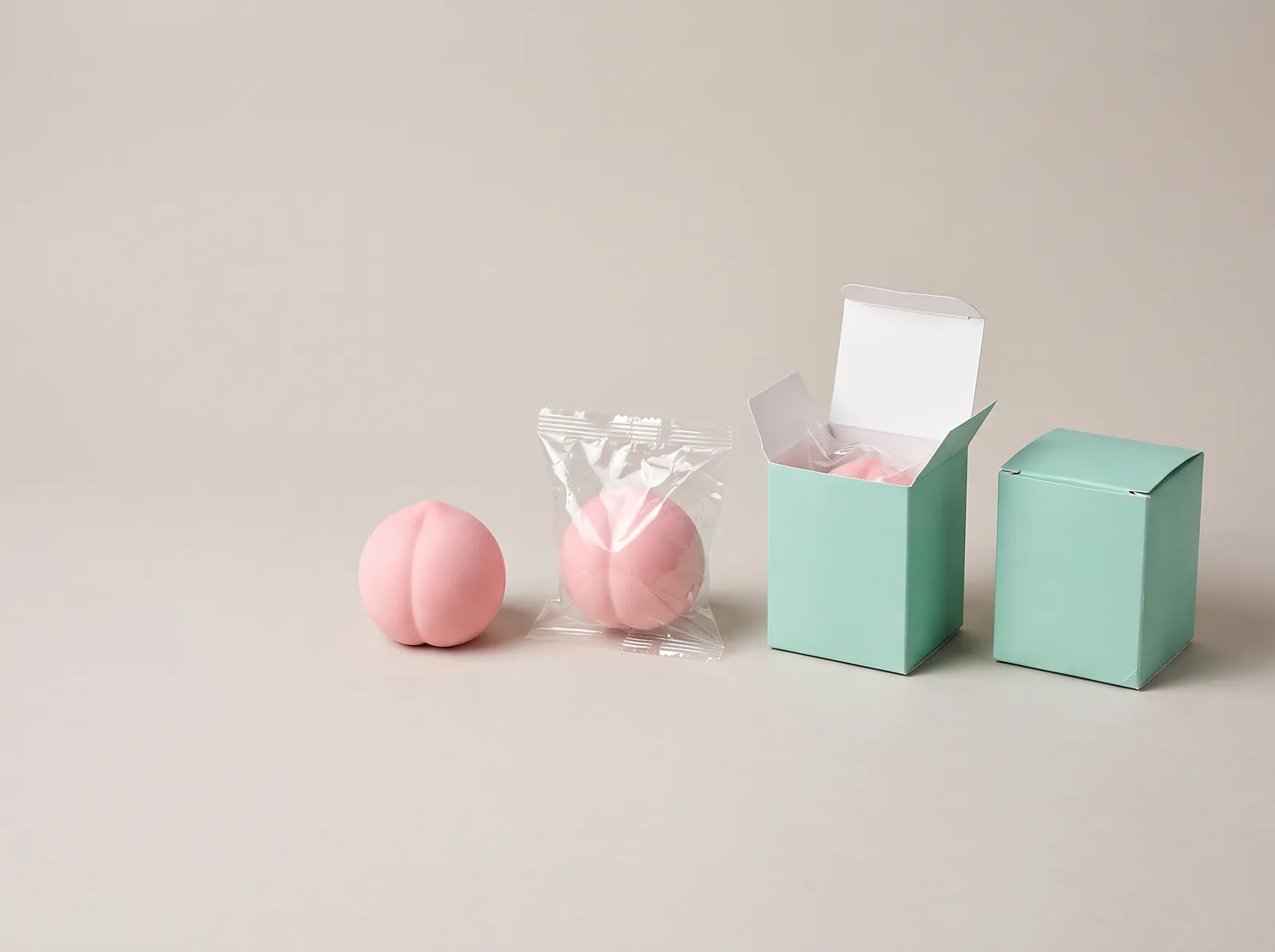 Step by step squishy packaging: a pink foam squishy, the same squishy heat-sealed in a bag, then placed in a mint box